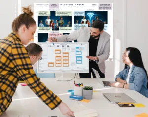 Professioneel team werkt samen aan een business case met behulp van het Solutioncy Platform op een computer, in een kantooromgeving met de Solutioncy Canvas zichtbaar op de achtergrond.